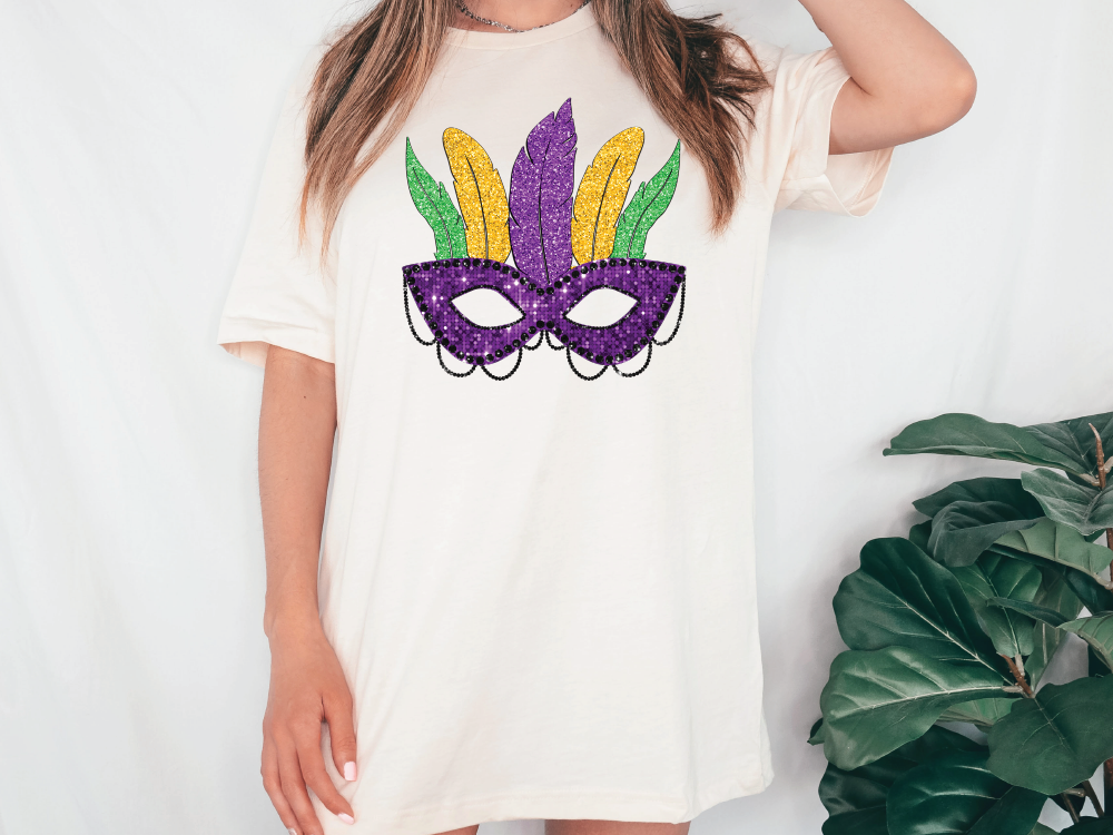 a woman wearing a t - shirt with a mardi gras mask on it