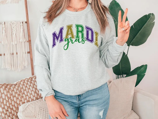 a woman wearing a mardi gras sweatshirt holding a peace sign