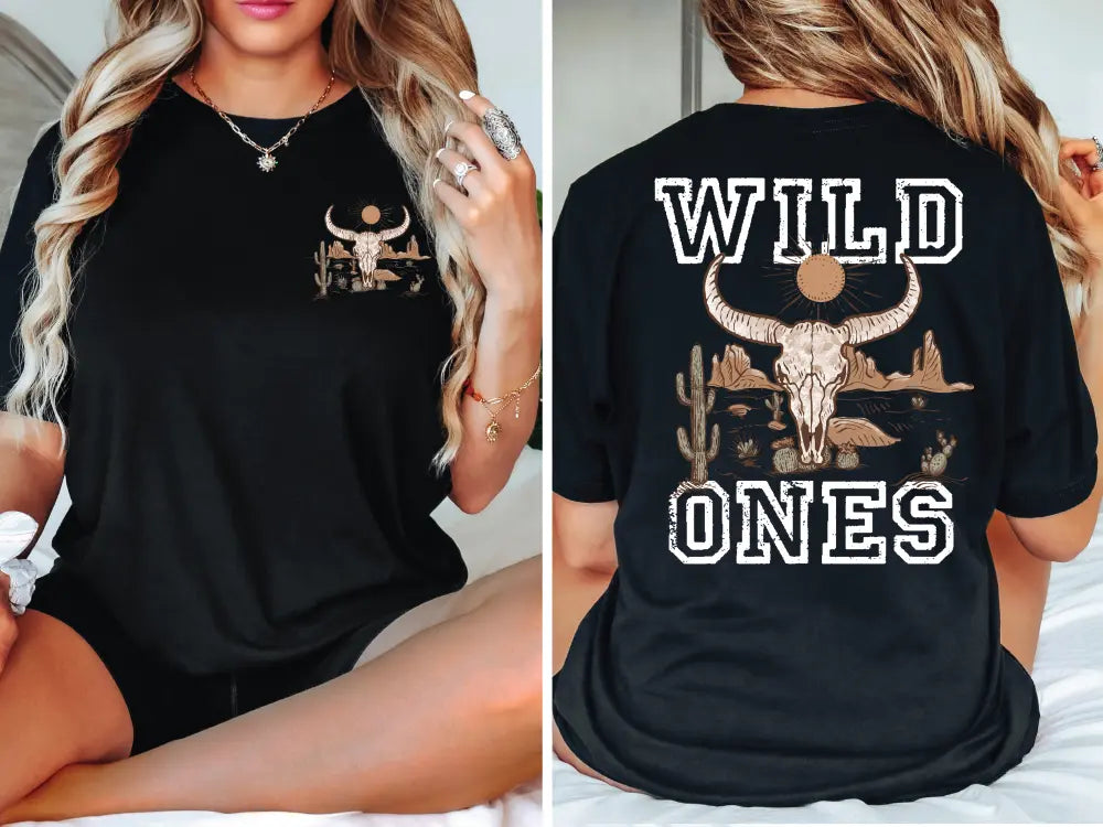 a woman sitting on a bed wearing a black shirt with wild ones on it