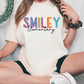 a woman sitting on the ground with a smiley t - shirt on