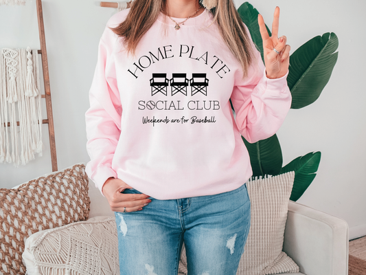 a woman wearing a pink sweatshirt that says i home plate social club