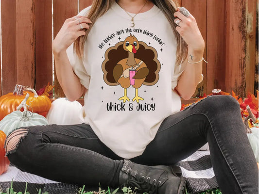 a woman sitting on the ground wearing a t - shirt with a turkey on it