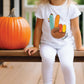 a little girl sitting on a porch next to a pumpkin