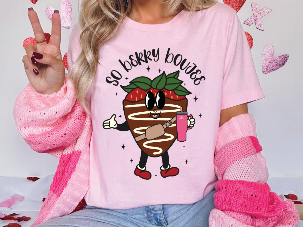 a woman wearing a pink shirt with a strawberry on it