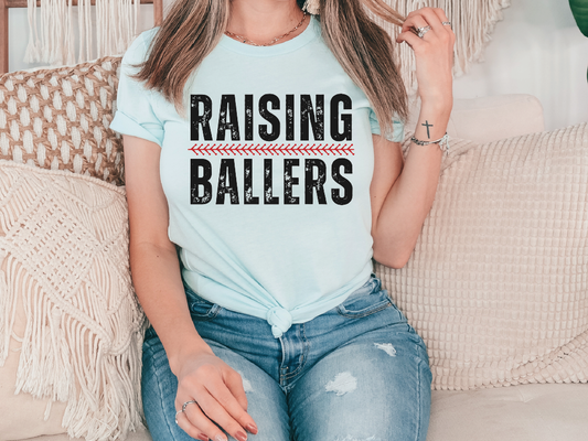 a woman sitting on a couch wearing a t - shirt that says raising ballers