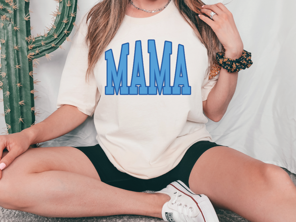 a woman sitting on the floor wearing a shirt that says mama