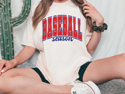 a woman sitting on the ground wearing a baseball season t - shirt