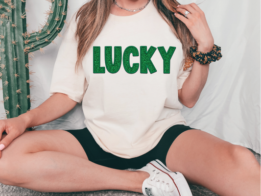a woman sitting on the floor wearing a lucky t - shirt